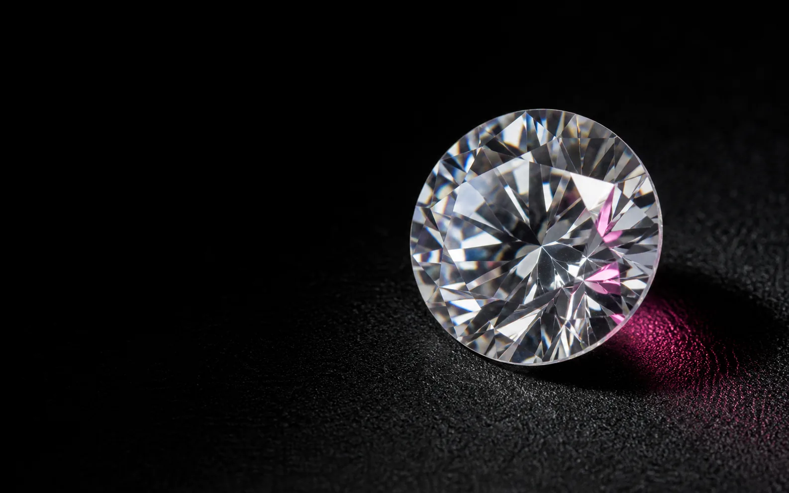 Diamante sciolto a taglio brillante osservato su una superficie gemmologica nera
